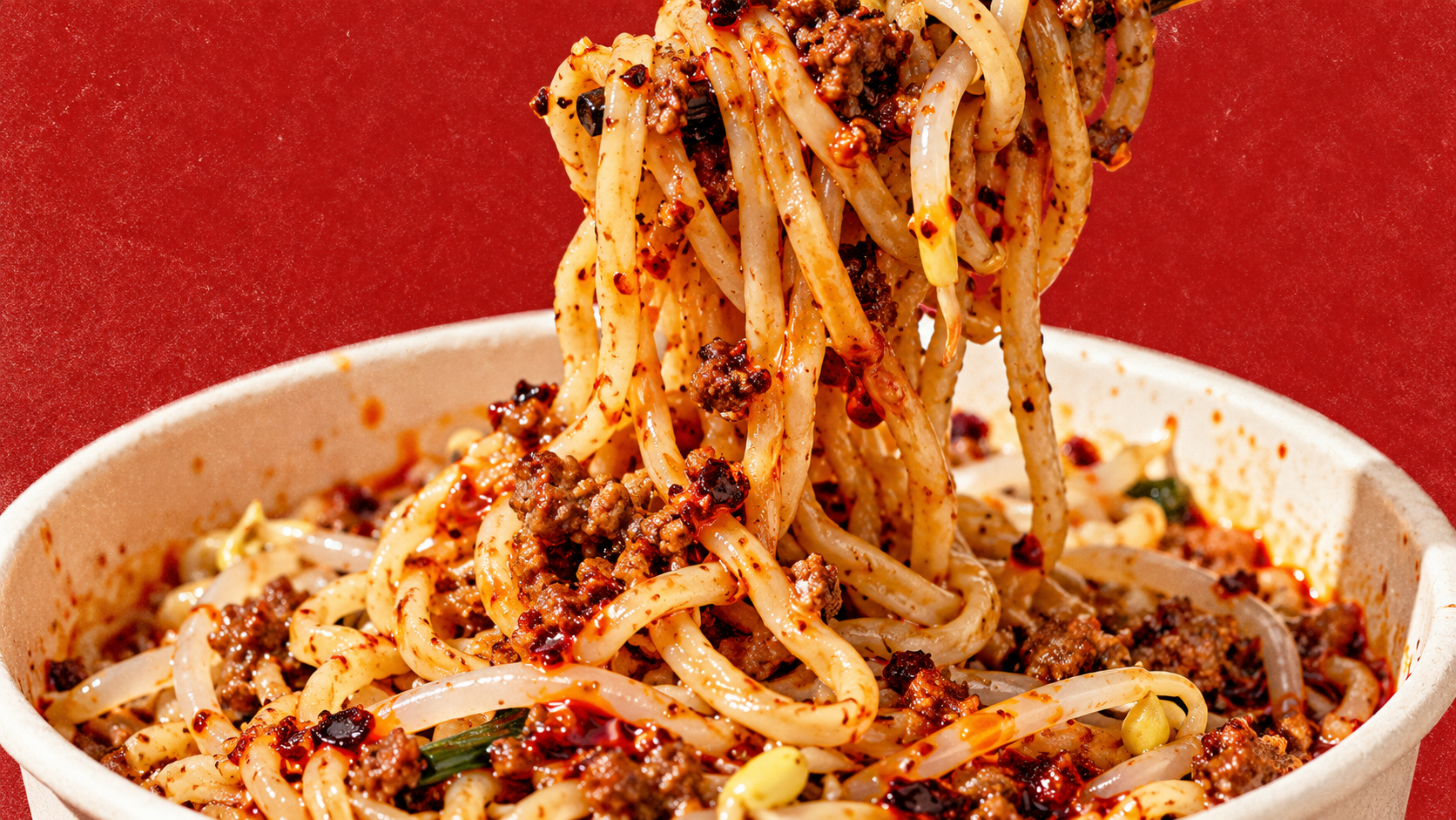 Close-up of wheat noodles glossed with red chili oil, illustrative image